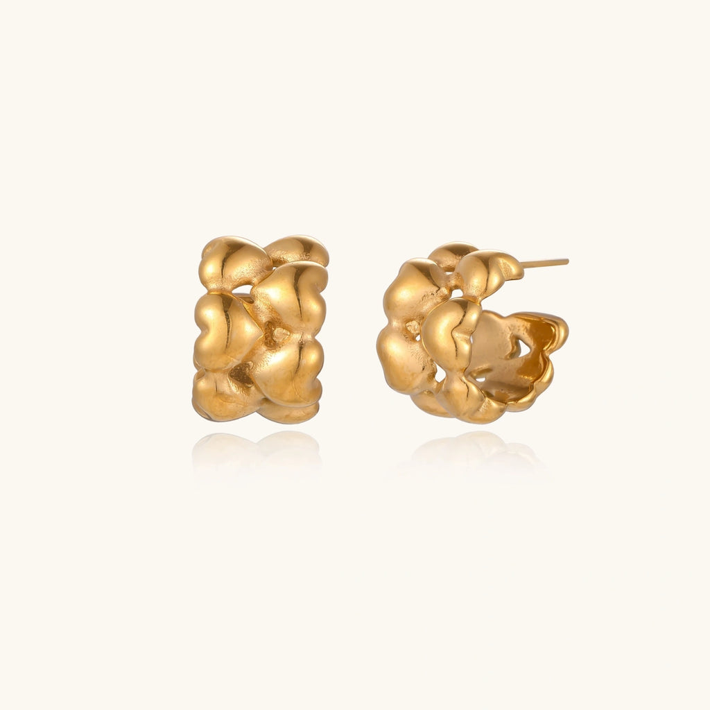 Close-up of gold-plated twisted rope huggie hoop earrings with brushed finish on white background.