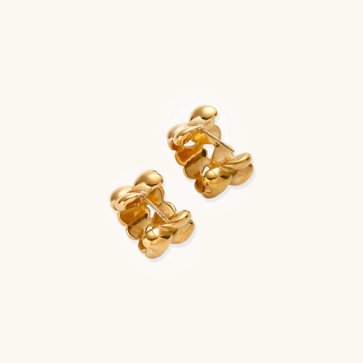 Close-up of gold-plated twisted rope huggie hoop earrings with brushed finish on white background.