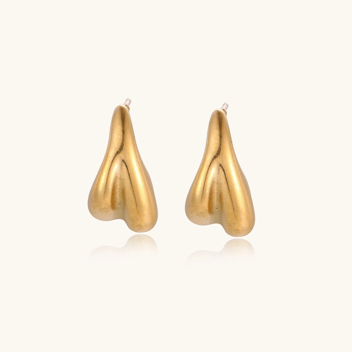 Organic sculptural gold stud earrings with fluid matte finish on cream background